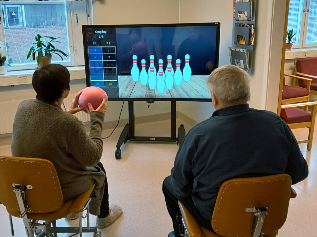 Two people are playing with YetiCare's YetiBowling game. 