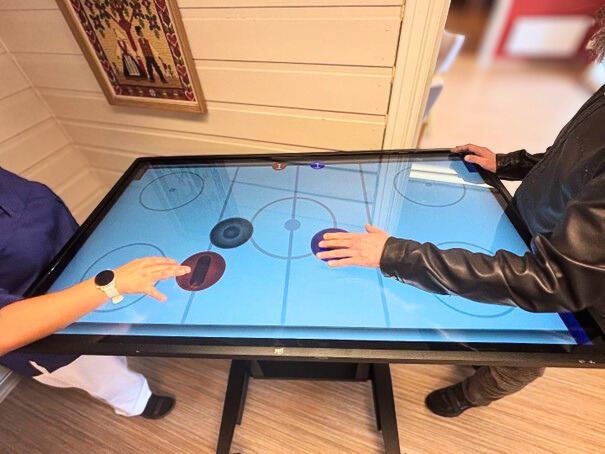 A nurse and a client are playing YetiHockey.